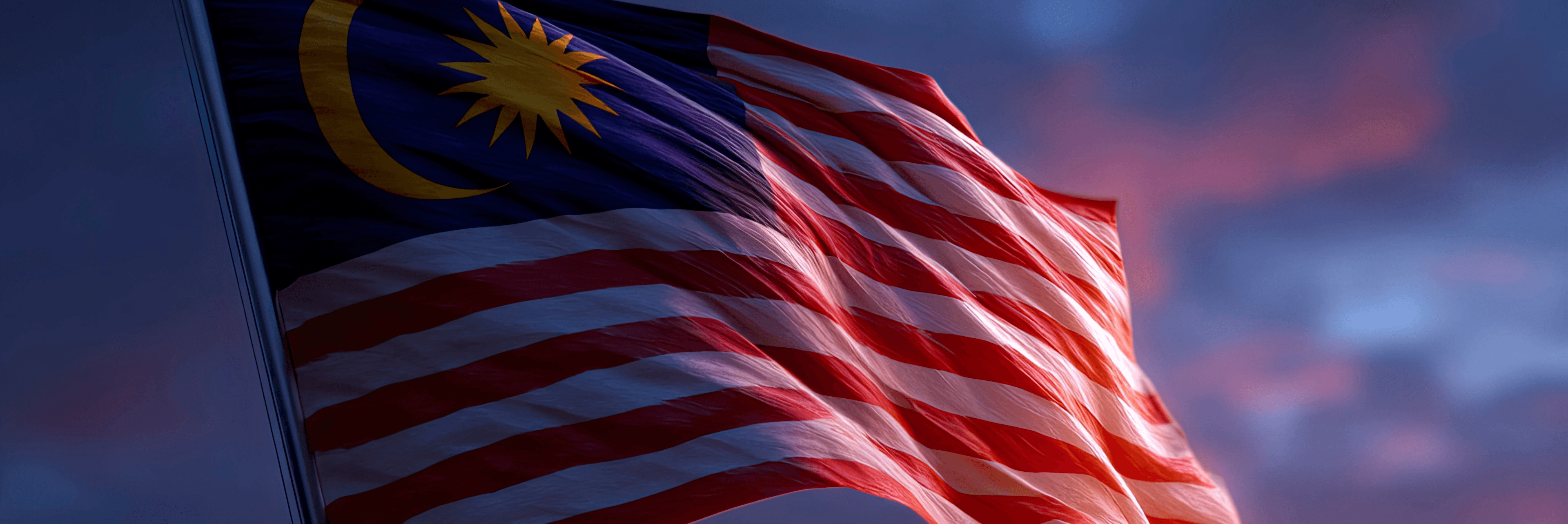 Malaysian flag waving dramatically against a moody blue and red cloudy sky, featuring the crescent moon, 14-pointed star, and red and white stripes