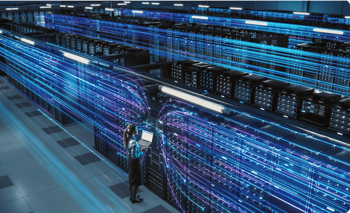 Female IT engineer standing in a large enterprise data center with glowing blue and purple data stream visualizations flowing through rows of server racks