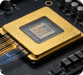 Close-up of a gold-plated CPU processor mounted on a circuit board with fiber optic cables, representing high-performance computing hardware
