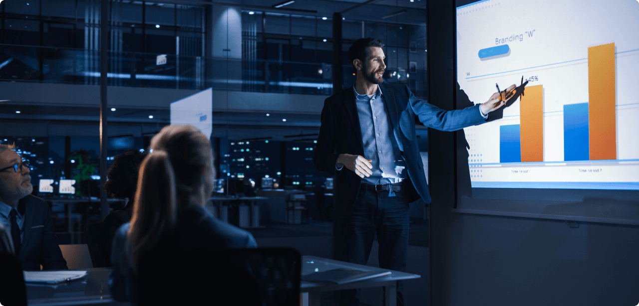 Business professional presenting a bar chart to colleagues during an evening meeting in a modern office