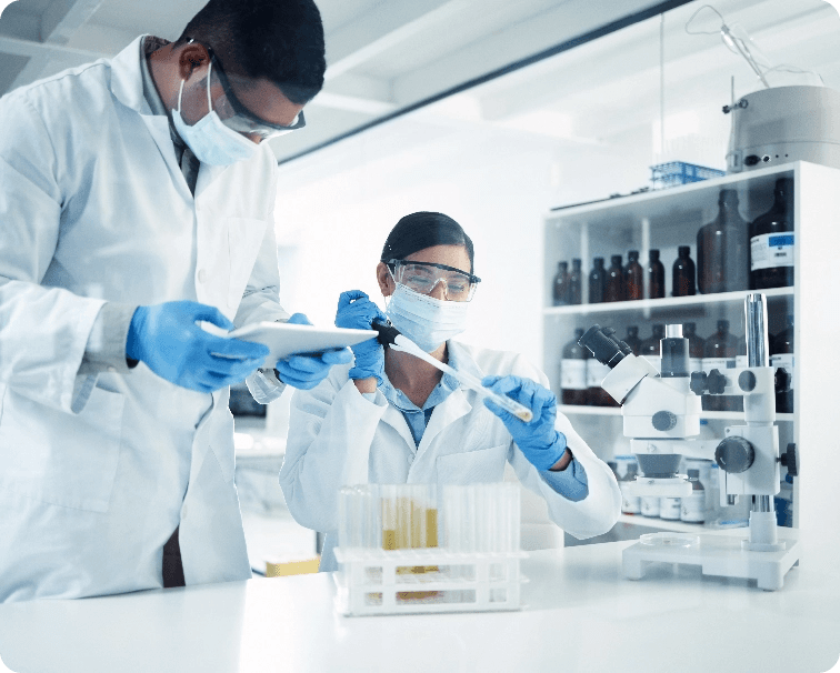 two chemists in lab coats and PPE working in a lab with test tubes and pipettes